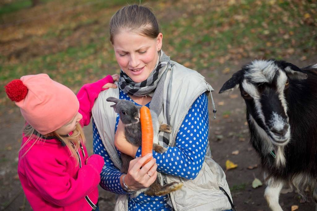 A mother and daughter are feeding animals at a petting zoo.