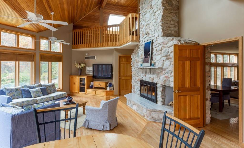 A warm lodge-inspired living room featuring a stone fireplace, natural wood details, and comfortable seating.