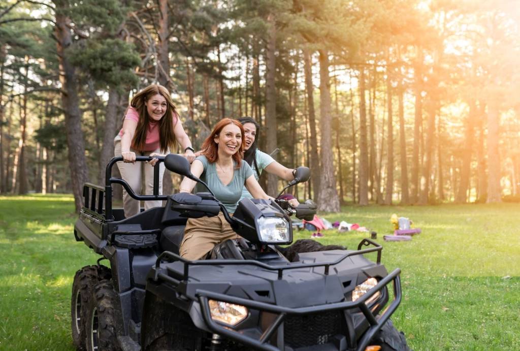 Three women enjoying an ATV ride through nature during an outdoor vacation