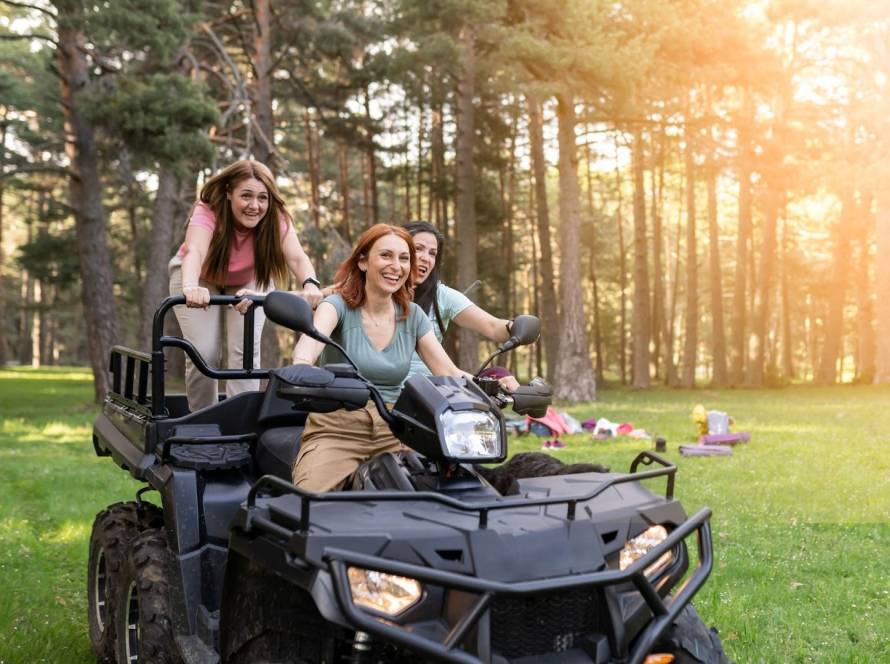 Three women enjoying an ATV ride through nature during an outdoor vacation