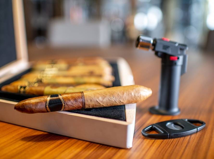 Luxury cigars in a humidor with a sleek lighter set on a wooden surface