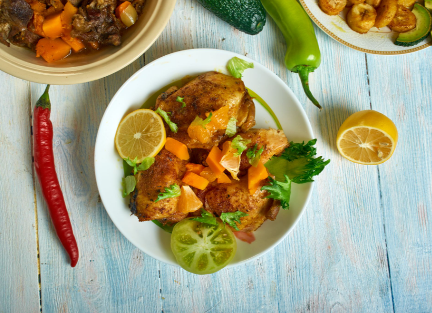 Dominican food featuring seasoned chicken thighs and assorted traditional side dishes, top view