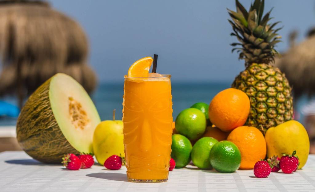 Tropical Dominican beverage with fresh fruits and a paper umbrella near the ocean