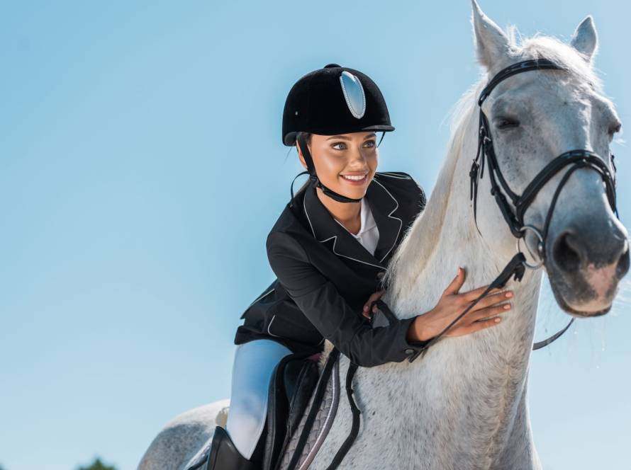 Portrait of a female equestrian riding a beautiful white horse 